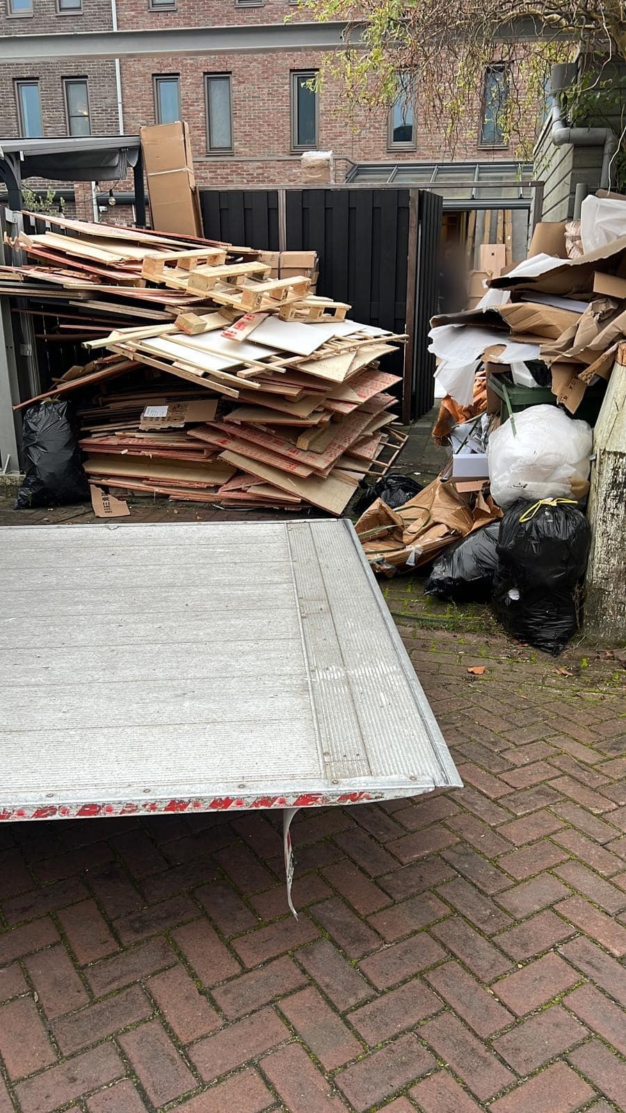 Stapel pallets en karton naast de open laadklep van de wagen