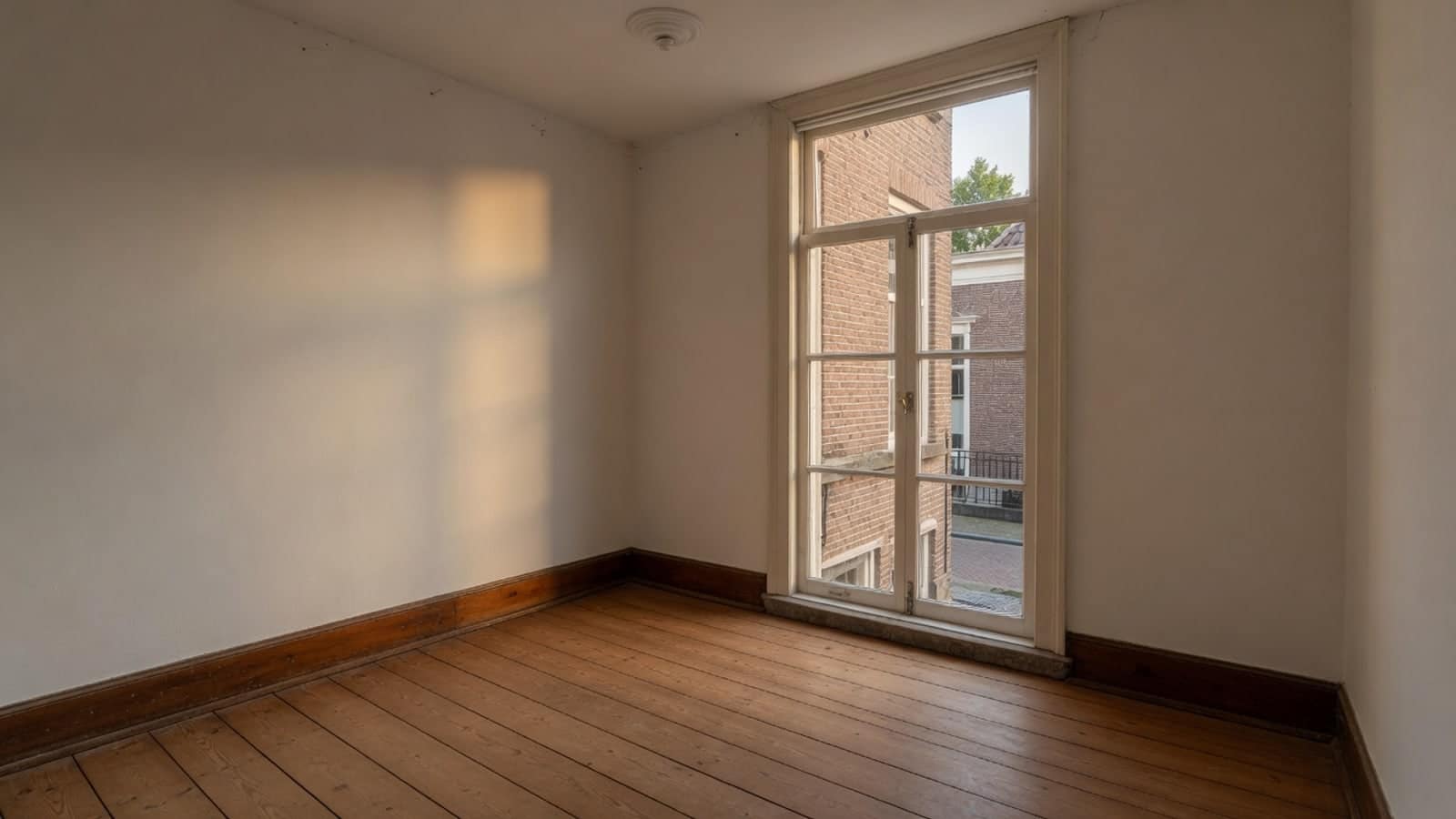 Lege kamer in een oud stadshuis, met de late zon langs de wand