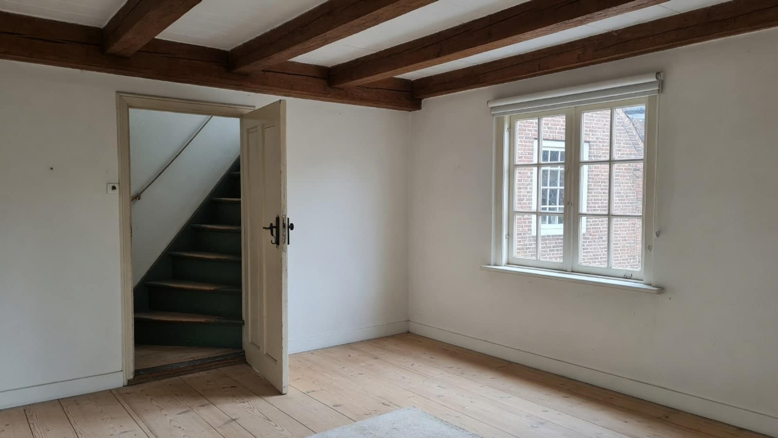 Lege bovenkamer met kleine roedenramen en een lage balkenzoldering