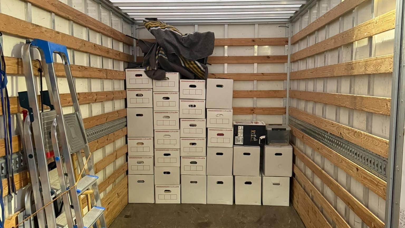 Gelijke stapels archiefdozen tegen de kopwand van een laadbak