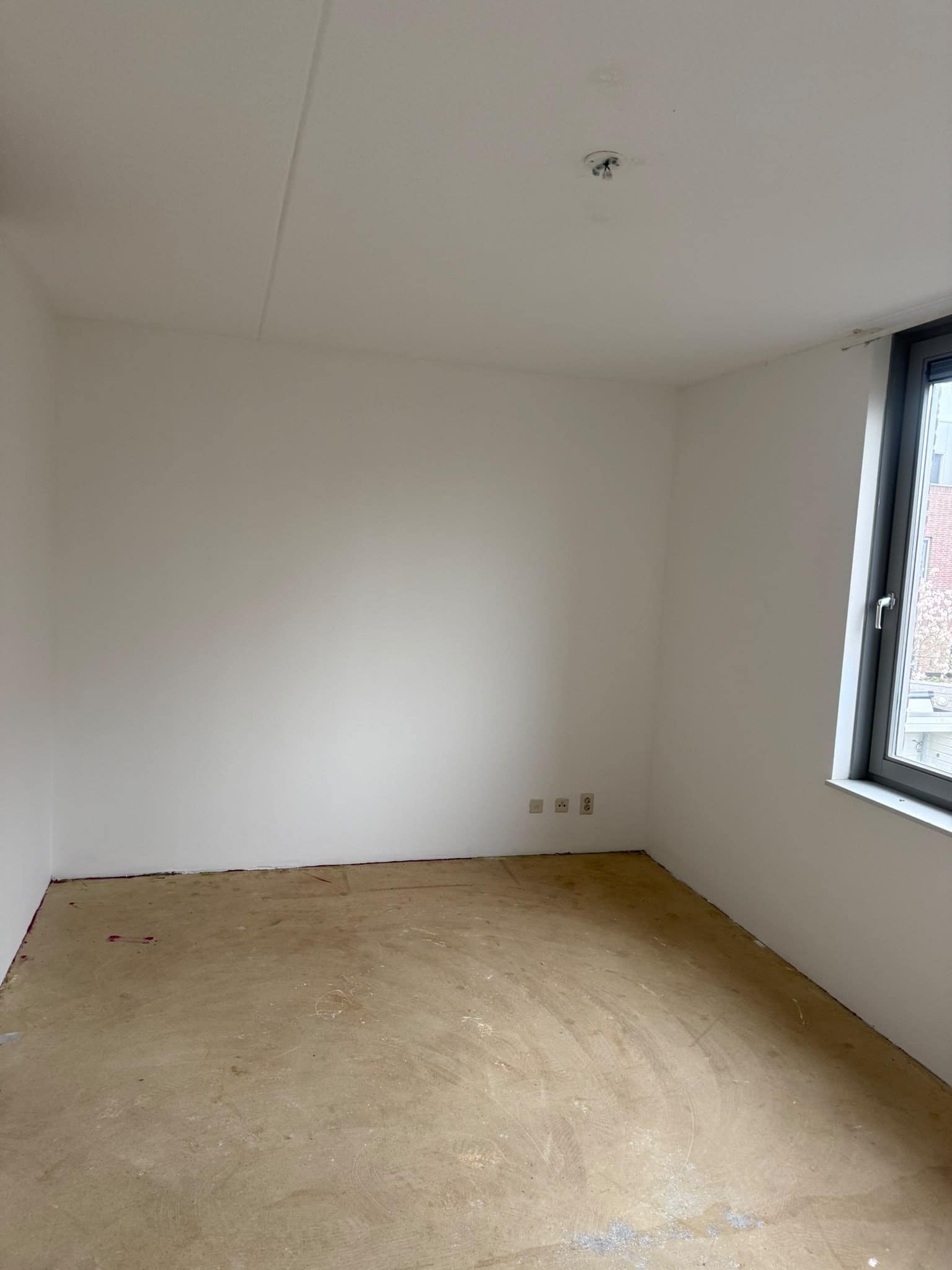 Lege kamer met wit geschilderde wanden en een raam op de straat