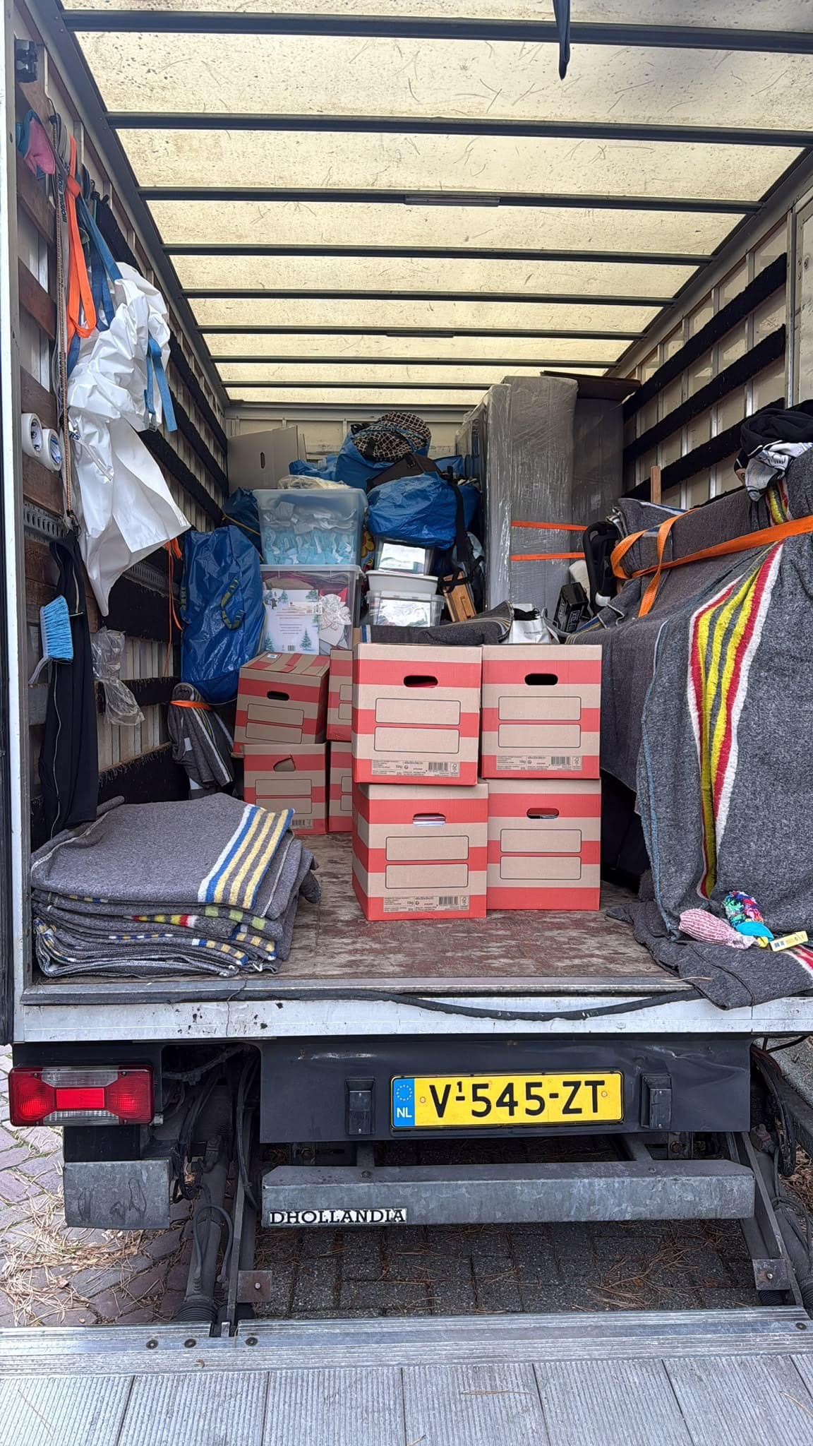 Geladen laadbak met dozen, dekens en spanbanden, gezien vanaf de laadklep