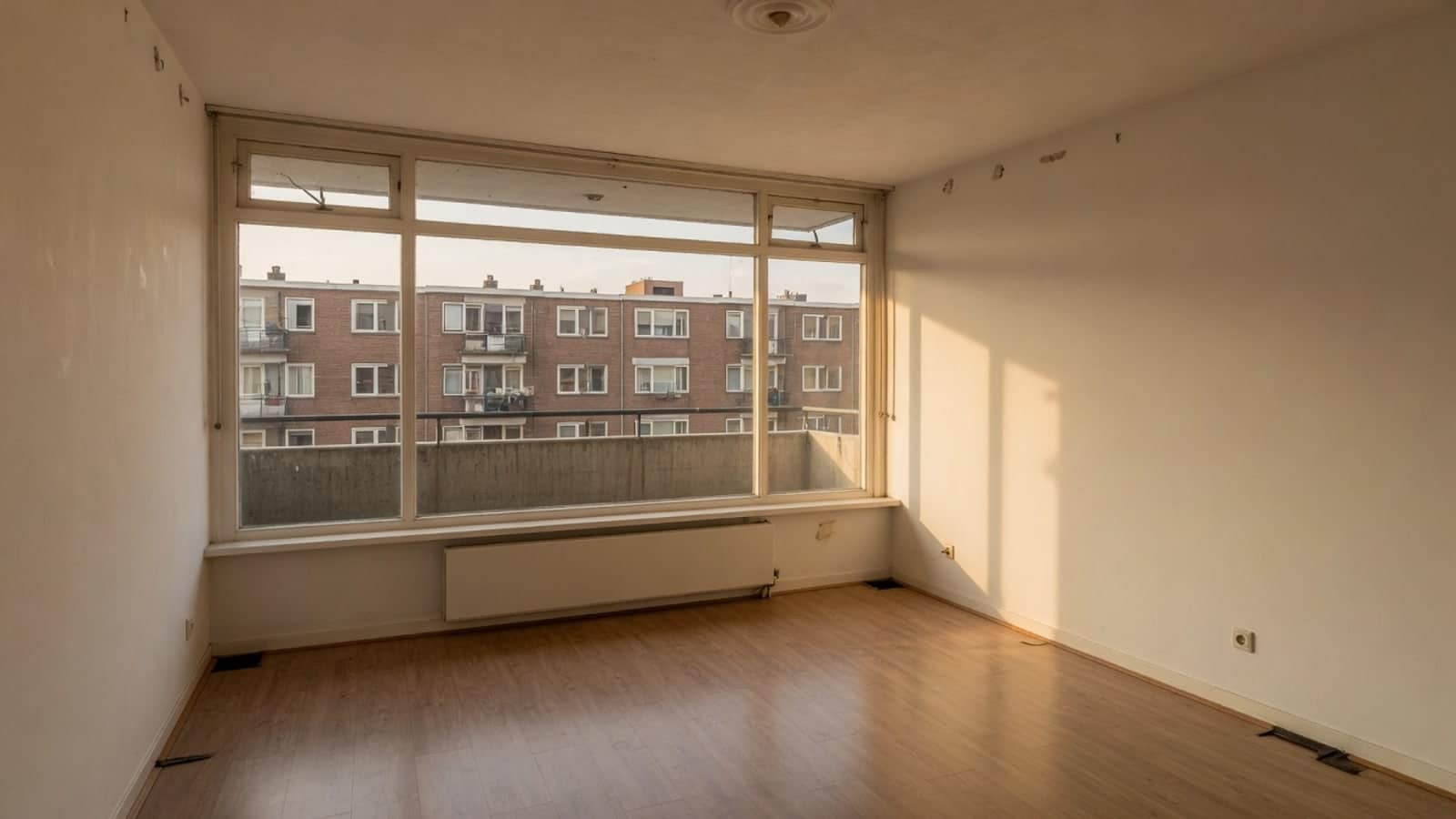 Rustige lege kamer met een breed raam en warm strijklicht over de vloer